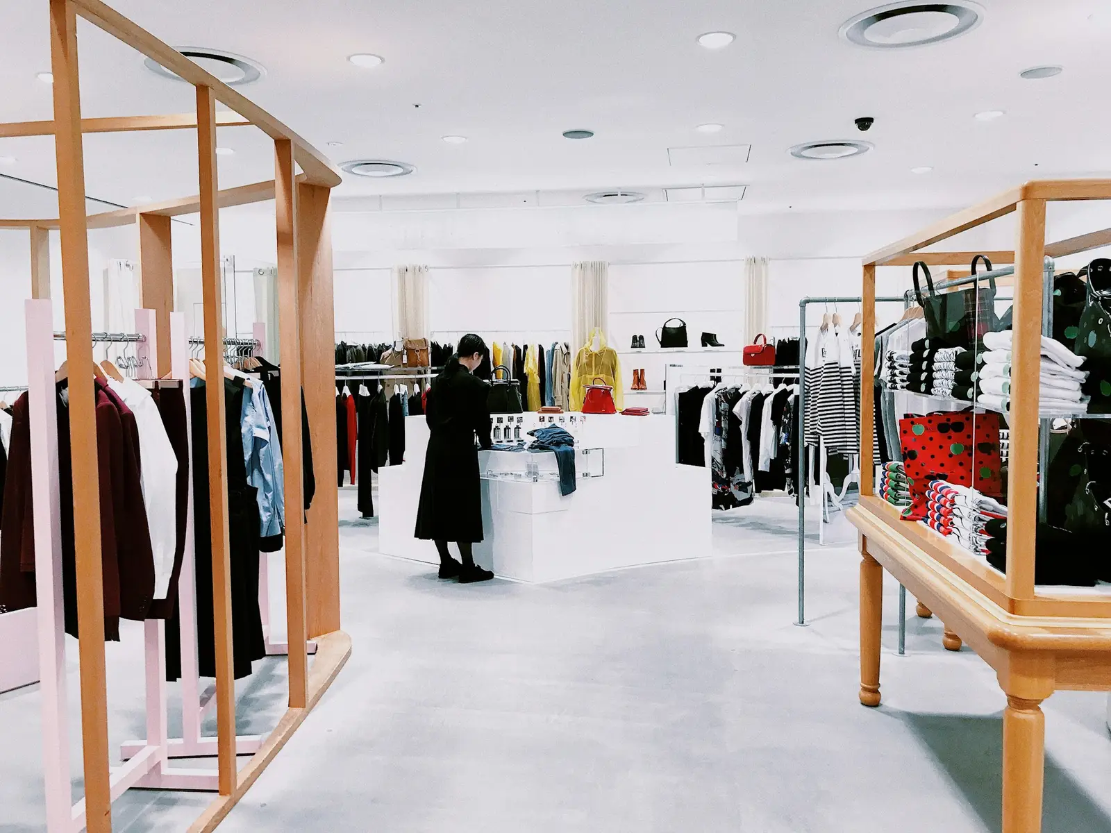 A bright clothing store with garments on wooden rails