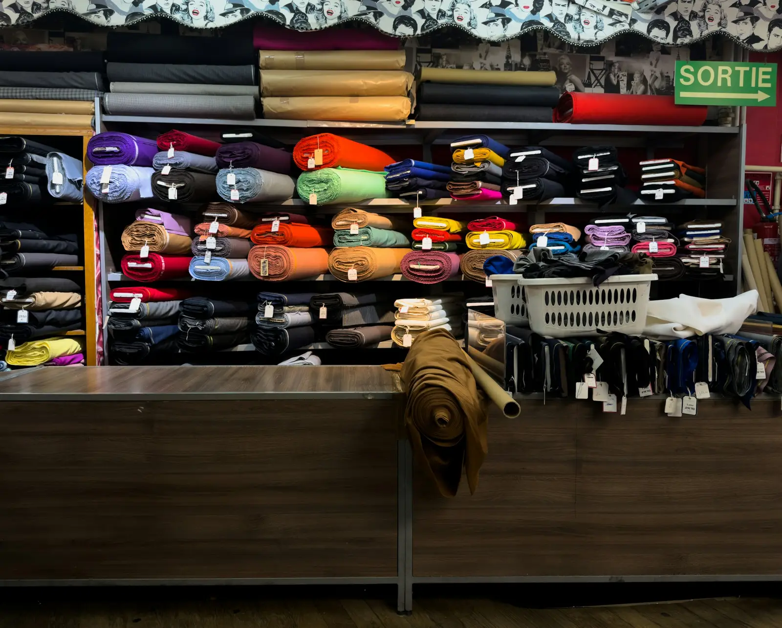 The counter of a fabric shop with shelves of folded cloth